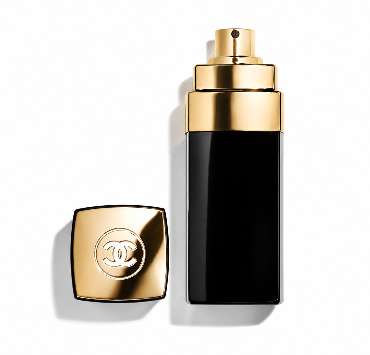 Chanel perfume bottle with a glossy black body and a shiny gold spray top, shown next to its detached square gold cap featuring the interlocking CC logo, on a white background.