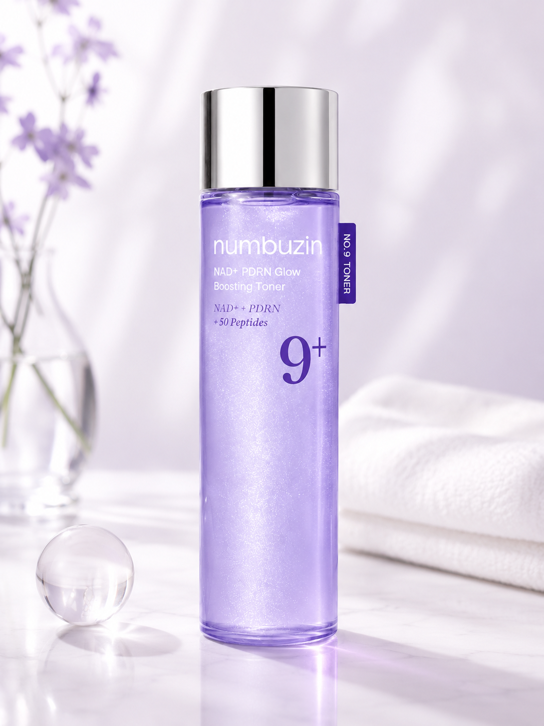 numbuzin No.9 NAD+ PDRN Glow Boosting Toner styled in a luminous lavender skincare setting with soft florals, clean white towels and reflective accents, emphasizing its hydrating, radiant and premium K-beauty aesthetic.
