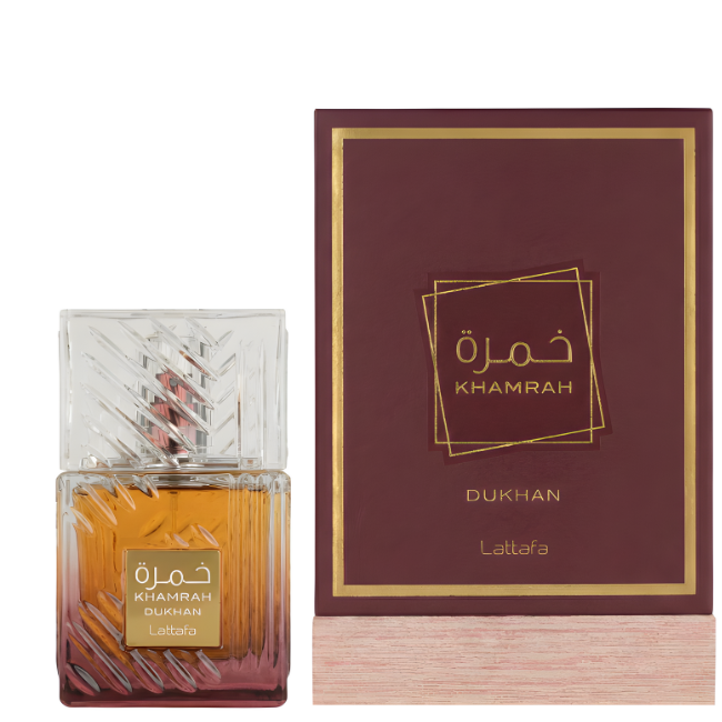 Lattafa Khamrah Dukhan Eau De Parfum in its ridged crystal-cut gradient glass bottle, presented alongside its matching deep burgundy-and-gold gift box resting on a light wooden base.