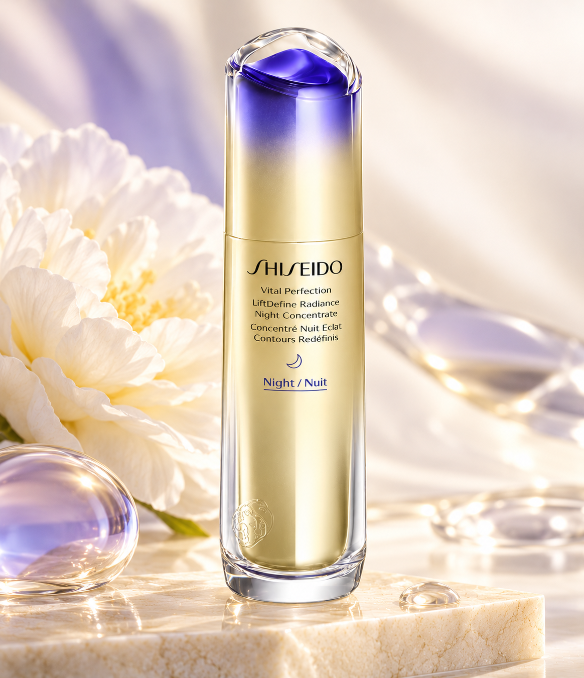 Shiseido Vital Perfection LiftDefine Radiance Night Concentrate in a luxurious gold and violet bottle, displayed on a cream marble surface with delicate ivory flowers, lavender glass accents and soft golden lighting. Premium Japanese nighttime skincare for smoother, firmer-looking and radiant skin.